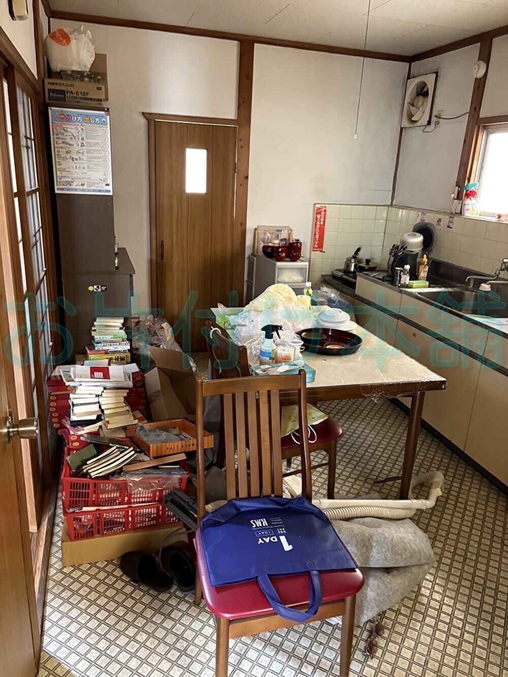 お片付け本舗による大津市のお片付け事例。テーブルや食器棚が置かれた片付け前のキッチン。