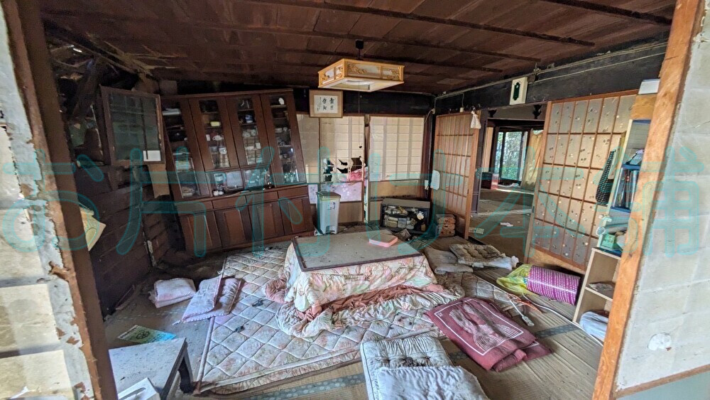 お片付け本舗による、滋賀県高島市での買取りの実例。コタツや床がたわんで傾いた食器棚などがあるリビング。