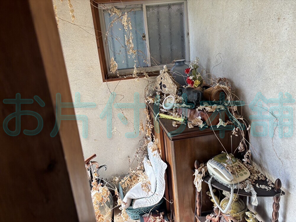 お片付け本舗が滋賀県近江八幡市で行った出張買取りの事例。棚や雑貨類が置かれ、枯れ葉がぶら下がる家の外回り。