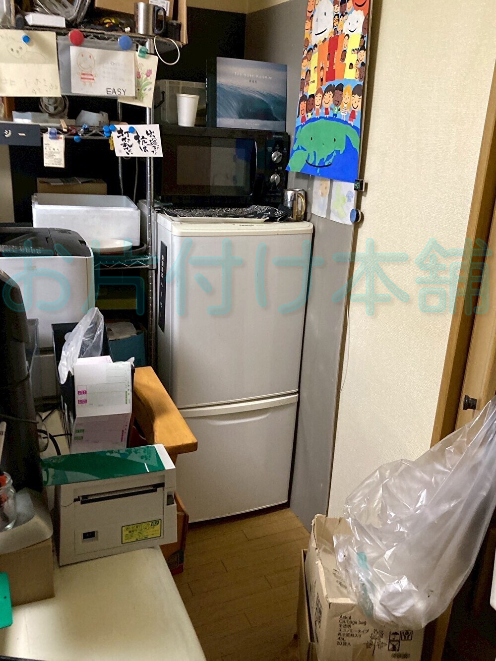 お片付け本舗によるお片付けの事例。片付ける前のテーブルや冷蔵庫やシュレッダーがある仕事部屋。