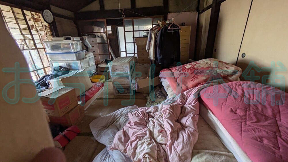 お片付け本舗による、滋賀県高島市での買取りの実例。布団や服など、たくさんの物がある和室。